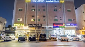 A multi-story building with signage for 'Nawara Serviced Apartments' and 'Rent a Car'. Several cars are parked in front. - Nawara AL  ASKARY - Economic (Riyadh)