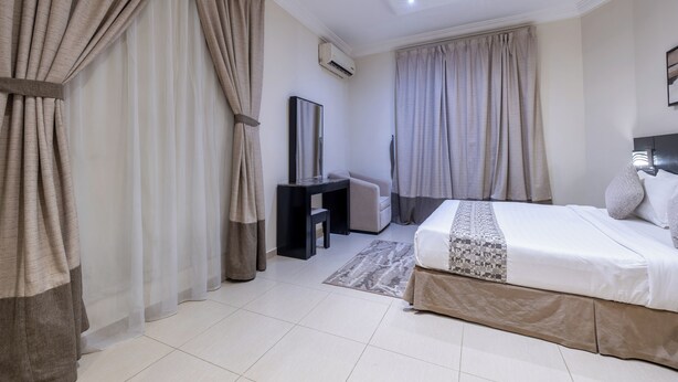 A hotel room with a bed, a desk, a chair, and curtains. - Nawara AL  ASKARY - Economic (Riyadh)