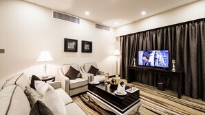 A modern living room with a sofa, armchairs, a coffee table, and a flat-screen TV. - Al Muhaidb Residence Serviced Apartments (Al-Hofuf)
