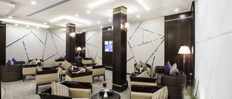 A modern lounge area with multiple seating options, including sofas and armchairs, arranged around a central coffee table.