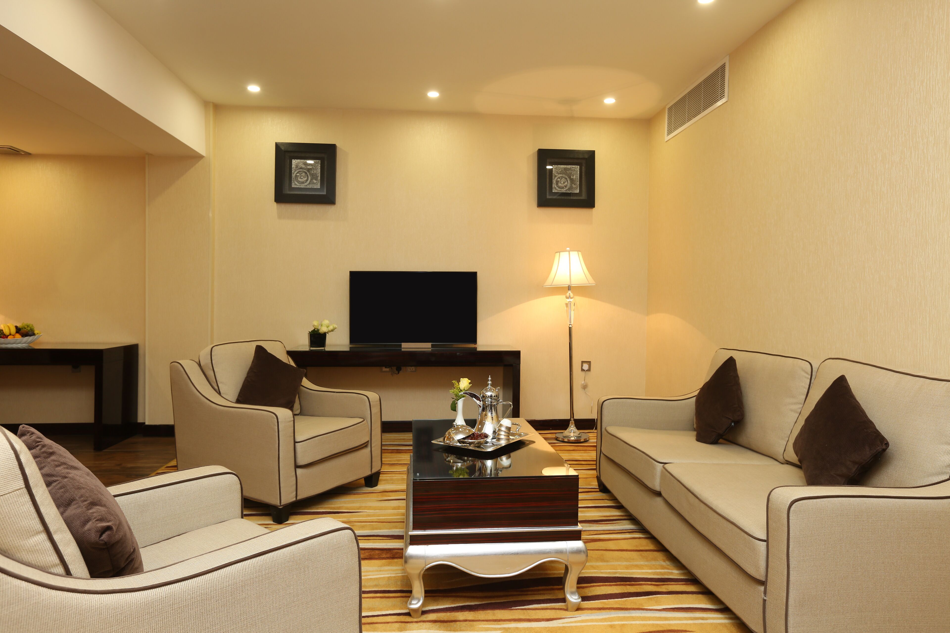 A modern living room with two sofas, a coffee table, a flat-screen TV, and framed pictures on the wall.
