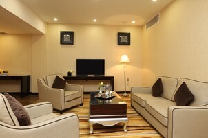 A modern living room with two sofas, a coffee table, a flat-screen TV, and framed pictures on the wall.