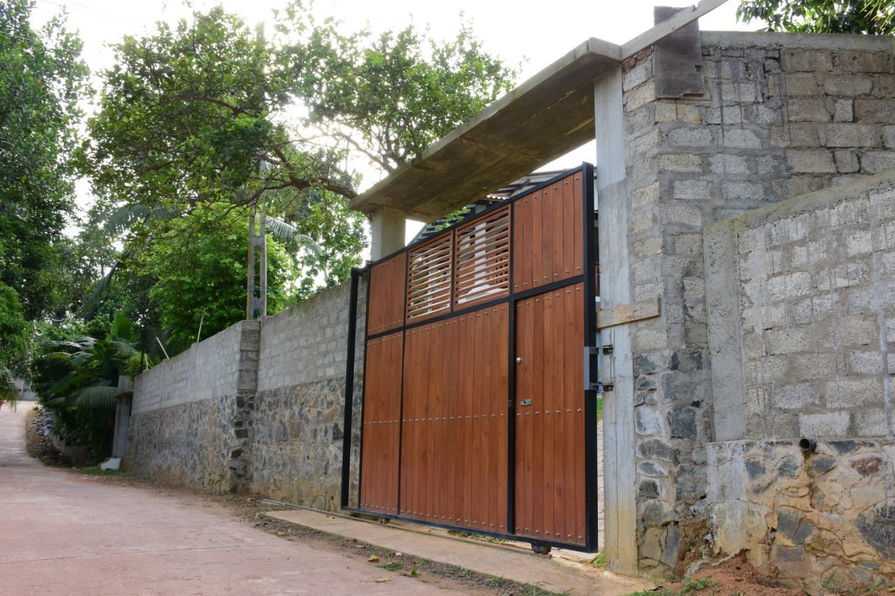 A gated entrance with a stone wall and a wooden gate.