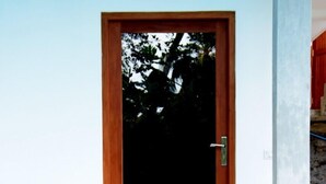 Ein moderner Hauseingang mit Holztür, zwei Pflanzgefäßen und einer Steinsäule.
