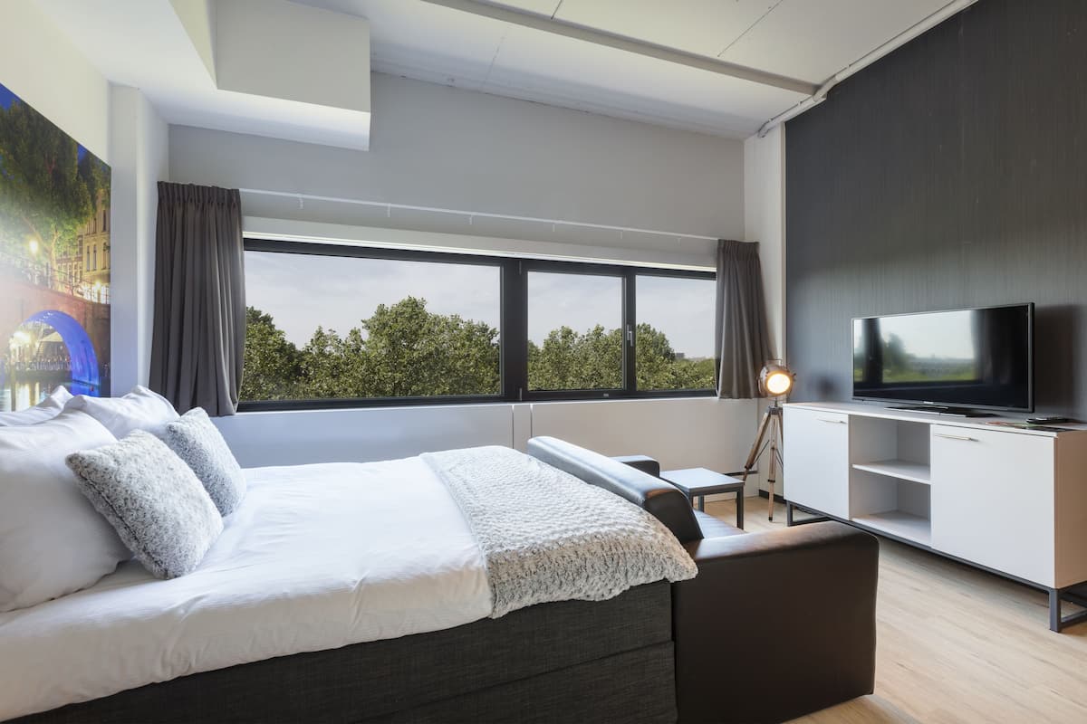 A modern bedroom with a large bed, a TV, and a desk.