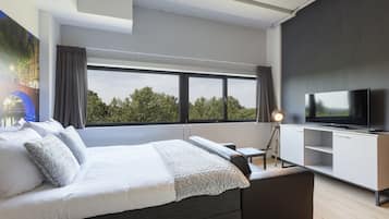 Une chambre d’hôtel moderne, dotée d’un grand lit, d’un bureau, d’une télévision et offrant une vue sur l’extérieur.