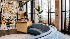 A modern reception area with a curved blue sofa, a wooden reception desk, and a large potted plant.