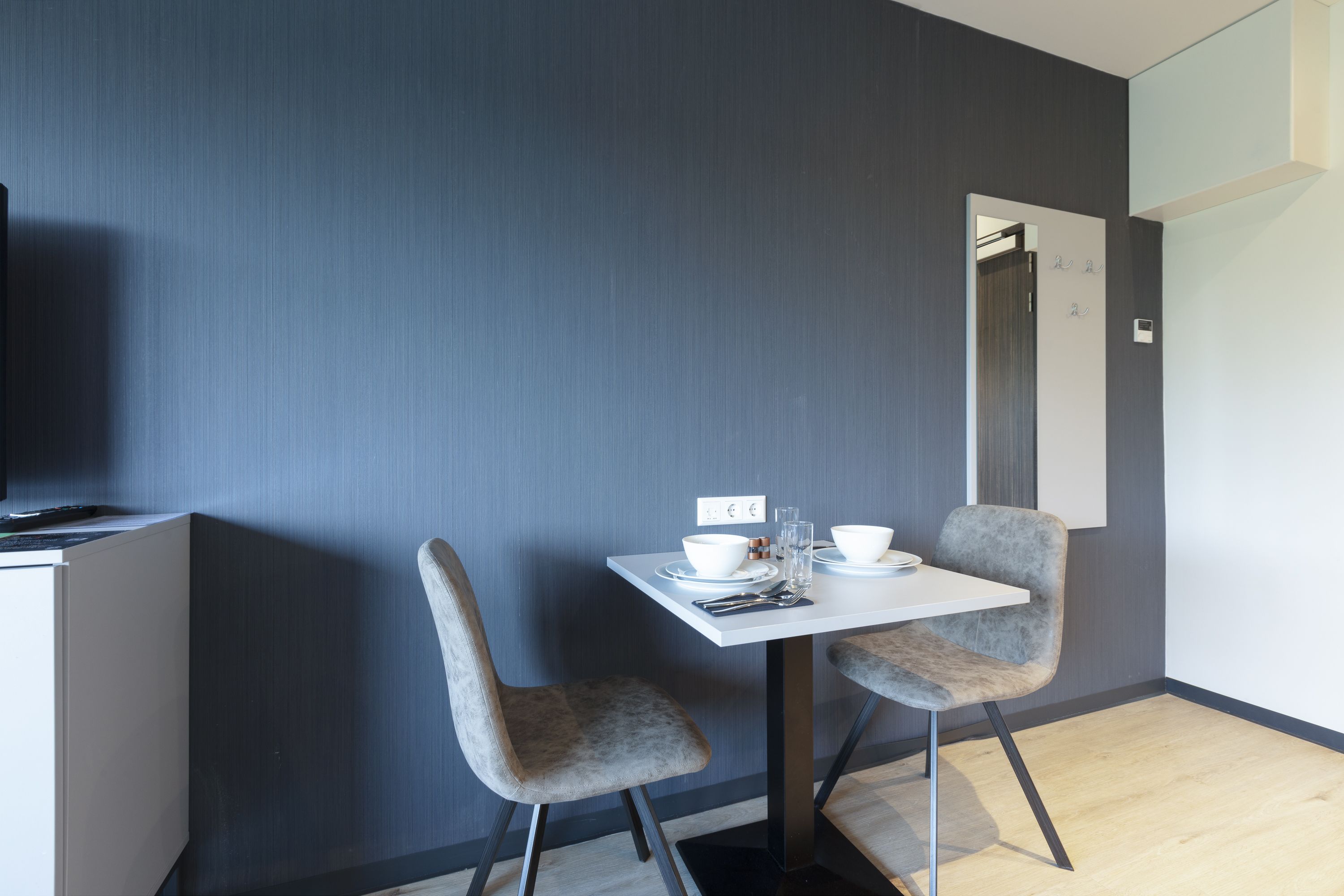 A modern dining area with two grey upholstered chairs, a white table, and a small white bowl.