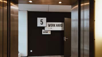 An elevator interior with a sign reading "5 WORK HARD" and "SKYBOX" on the wall.
