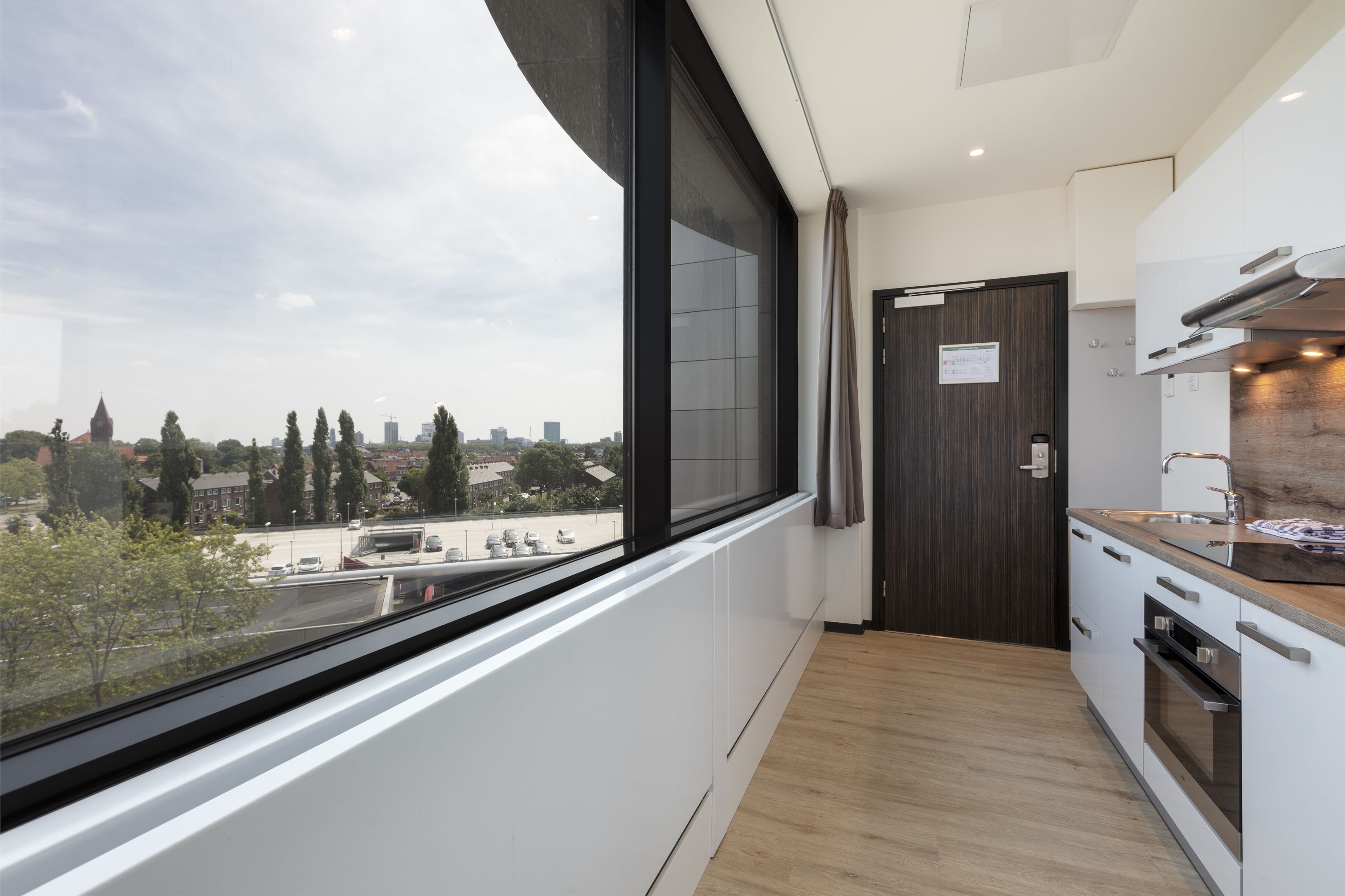 Una cocina moderna con un amplio ventanal, vista a la ciudad y suelo de madera.