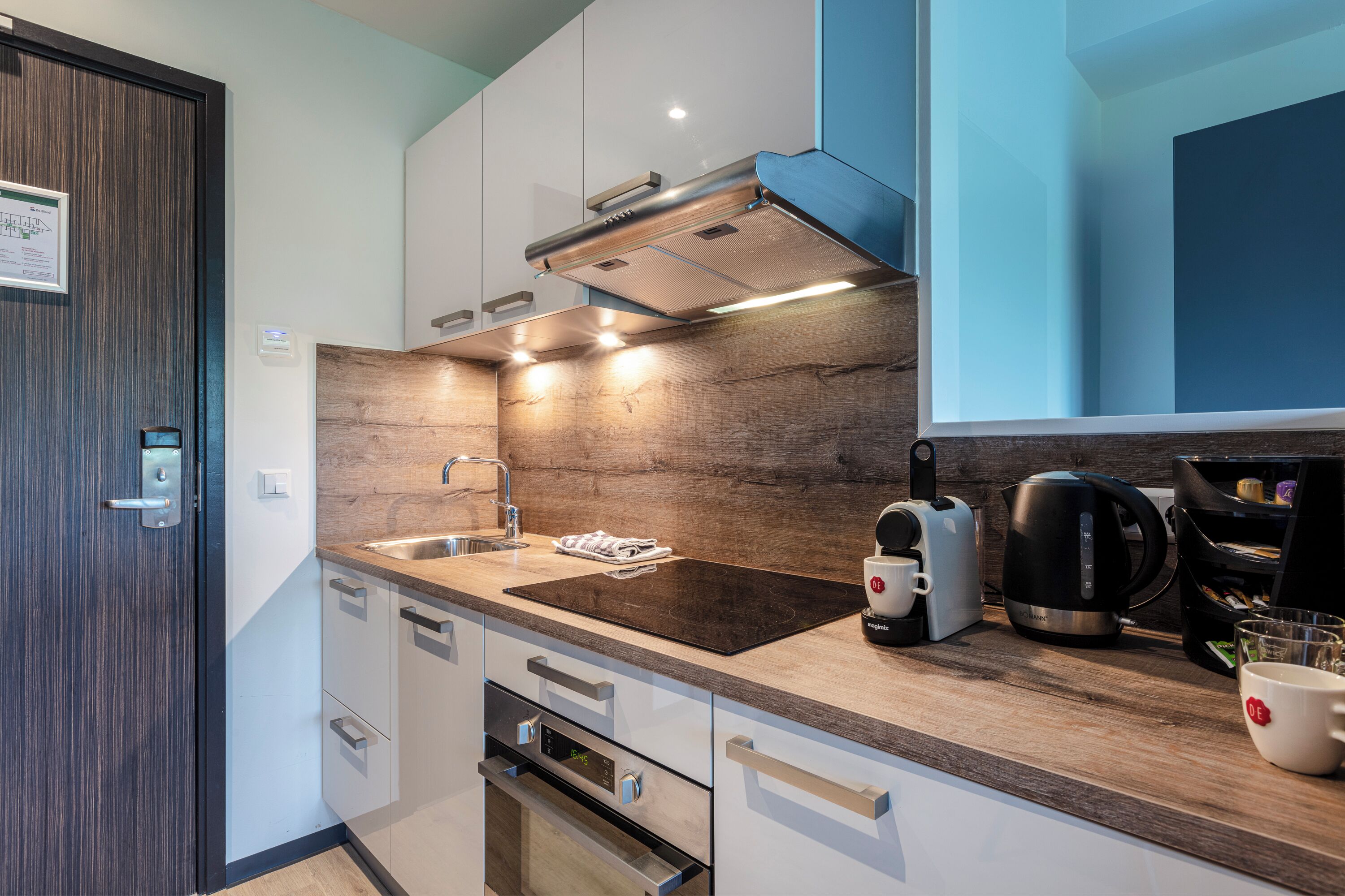 Una cocina moderna con encimera de madera, electrodomésticos de acero inoxidable y horno empotrado.
