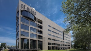 A modern building with the name "DE BLEND" on the facade, featuring multiple floors with large windows and a flat roof.