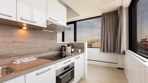 A modern kitchen with white cabinets, a wooden countertop, and stainless steel appliances.