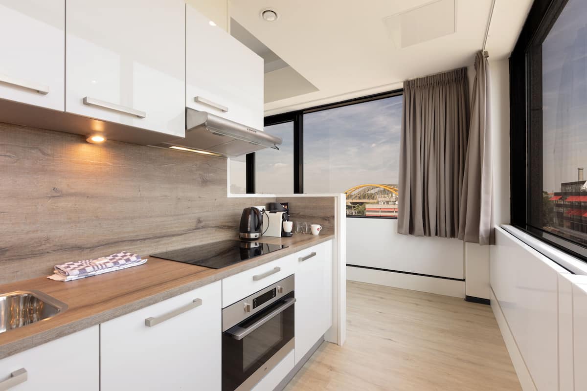 A modern kitchen with white cabinets, a wooden countertop, and a stainless steel sink.