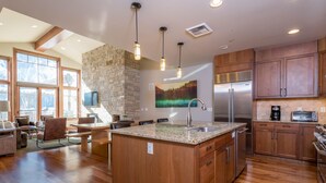 A spacious kitchen with a large island, wooden cabinets, and a stone accent wall. - Ketchum Penthouse 3 Blocks to Downtown (Ketchum)