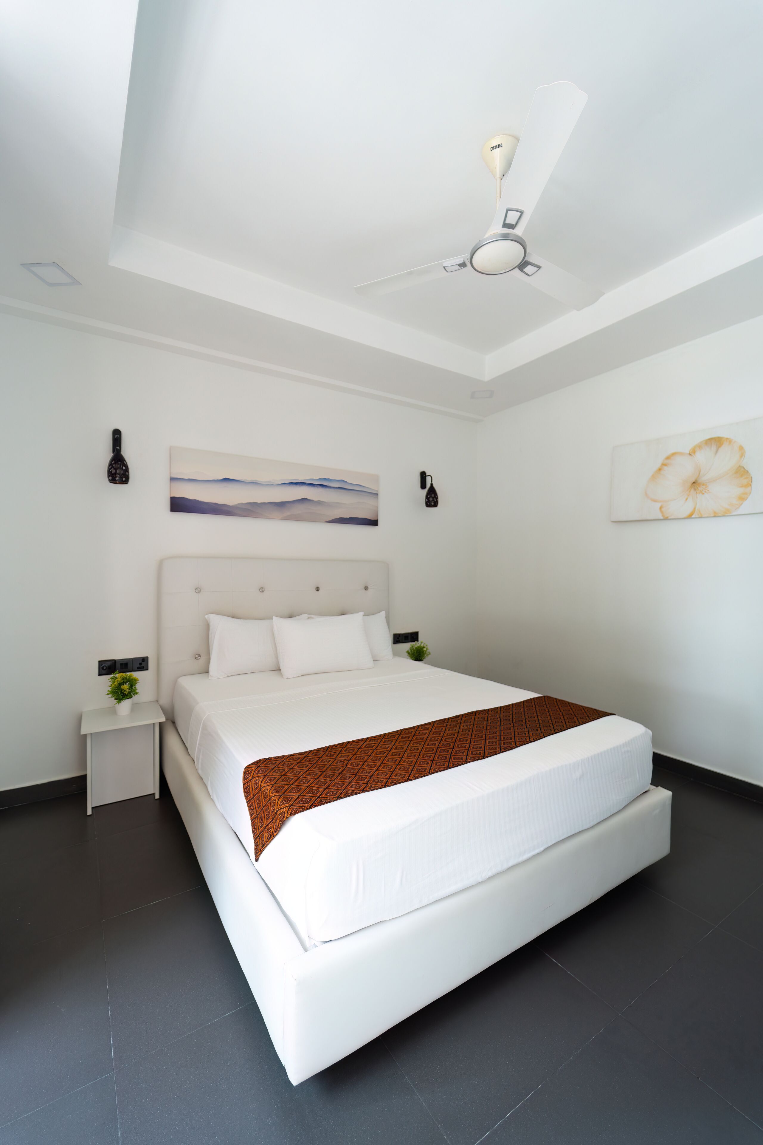 Una habitación de hotel moderna con una cama grande, un ventilador de techo y obras de arte en las paredes.