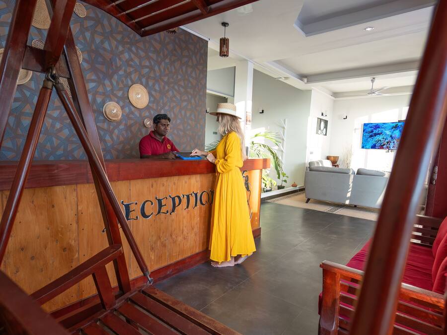 A reception area with a wooden reception desk labeled "RECEPTION," a man in a red shirt, and a woman in a yellow dress.