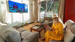 A living room with a sofa, armchairs, a coffee table, and a TV on the wall. - Silver Oasis Maldives (Huraa)