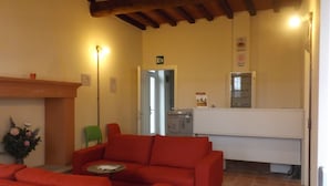 Eine Lobby mit roten Sofas, einem grünen Sessel, einem Empfangstresen und einem Kamin.