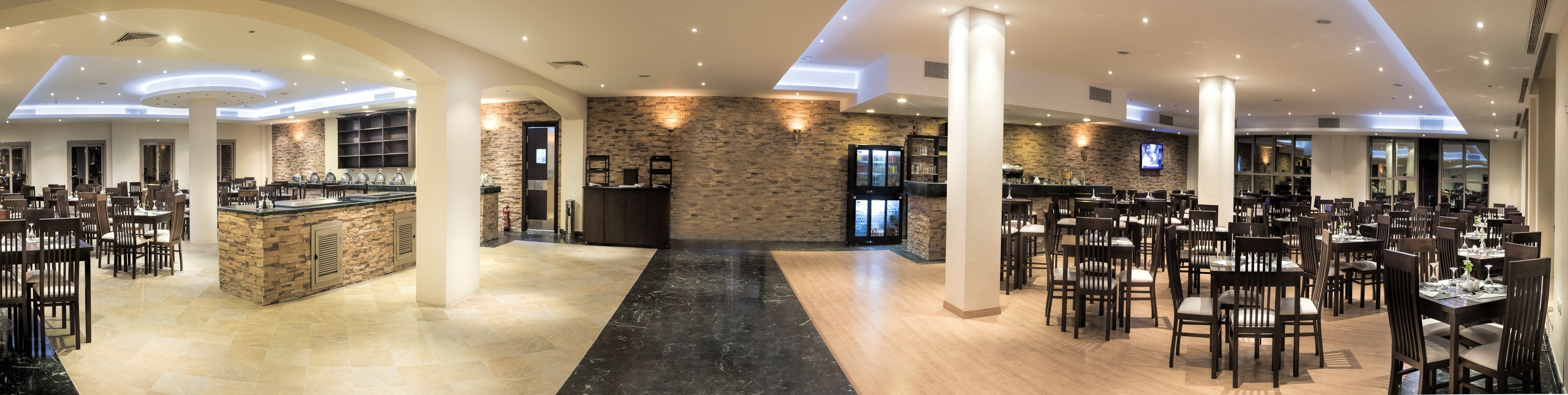 A spacious restaurant with multiple dining areas, a central bar, and stone accents.