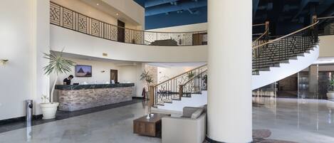 A spacious lobby with a reception desk, seating area, and a staircase leading to upper floors.