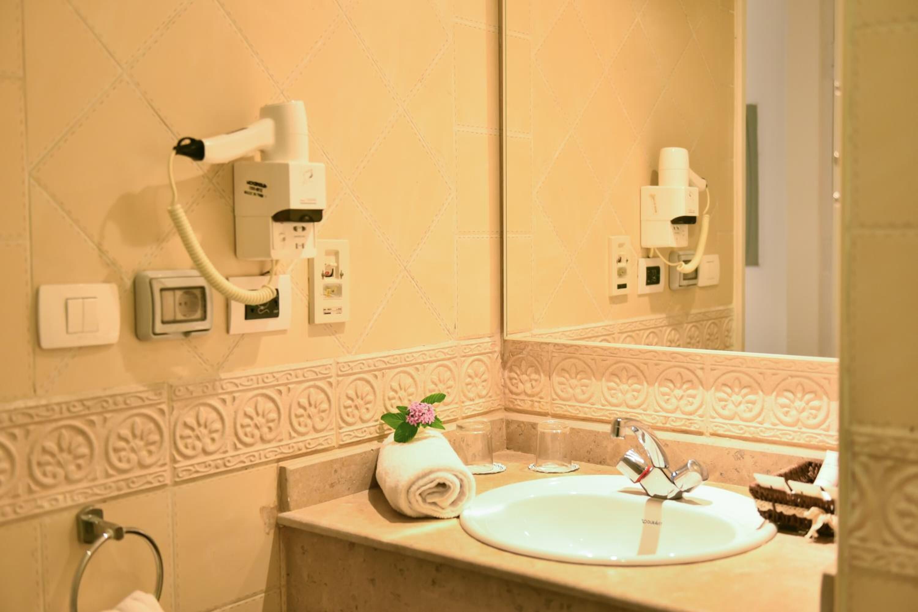 A bathroom with a sink, mirror, towel, and hairdryer.