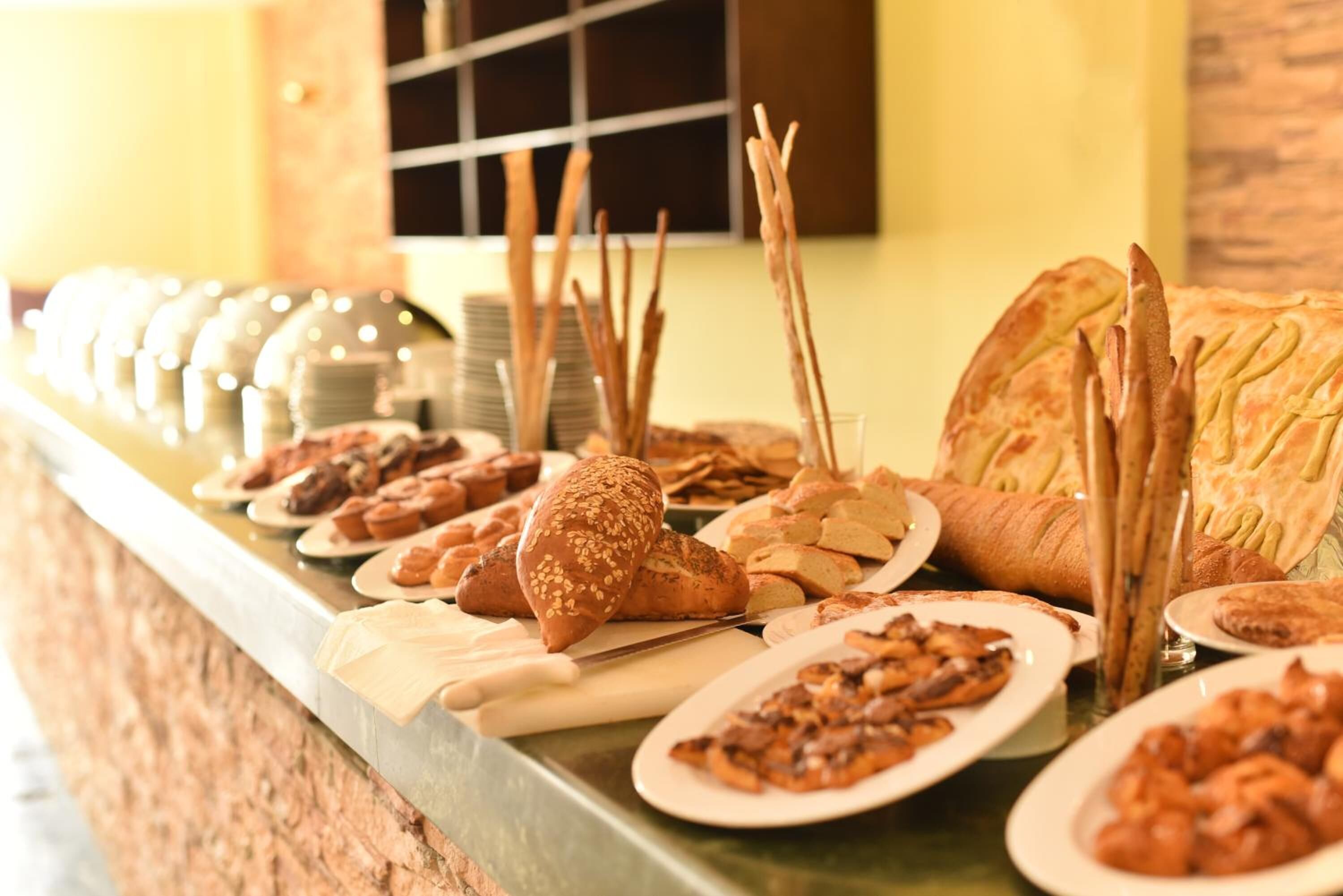 Un buffet con diversi pani, pasticcini e un'ampia pagnotta.