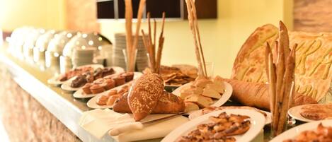 Un buffet con diversi pani, pasticcini e un'ampia pagnotta.