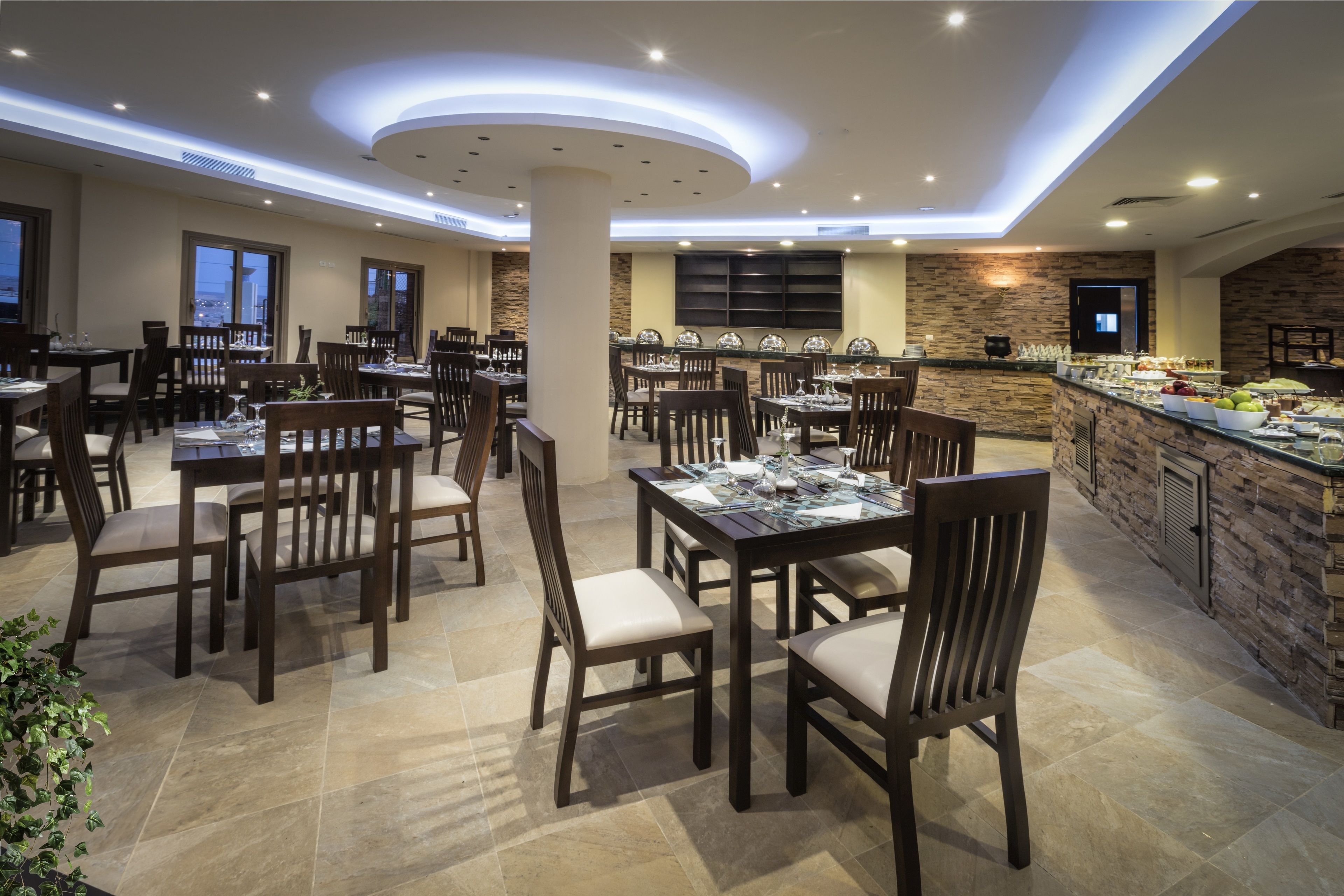 Un grand espace dédié à la salle à manger, avec plusieurs tables et chaises, un buffet et un mur décoratif en pierre.