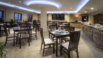 A spacious dining area with multiple tables and chairs, a buffet counter, and a stone accent wall.