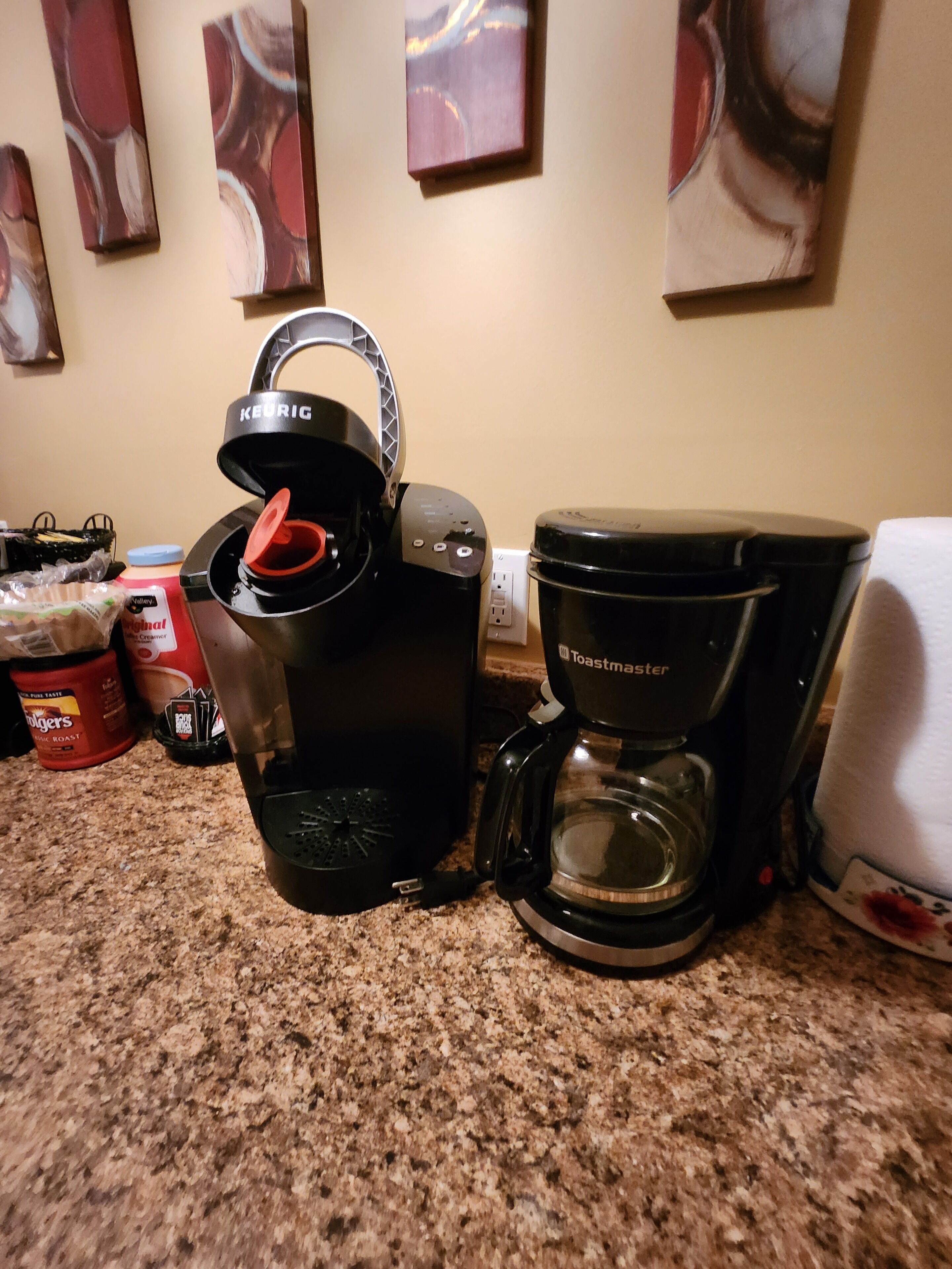 Une machine à café, un grille-pain et une cafetière sont posés sur le plan de travail de la cuisine.
