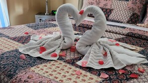 Een bed met een quilt met bloemenprint, een wandklok en een schilderij.