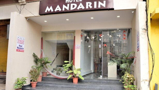 La entrada del Hotel Mandarin, con escalones que conducen a ella, plantas en macetas en los escalones, y un letrero que indica prohibido estacionar.