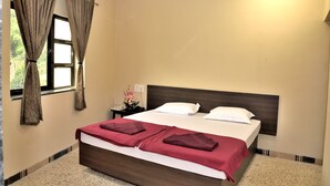Habitación de hotel con una cama grande, dos almohadas, una mesita de noche con lámpara y una ventana con cortinas.