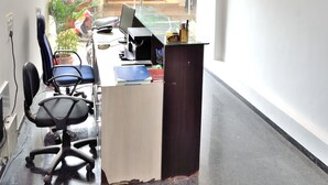 Una oficina moderna con escritorio, sillas y una computadora. Hay una ventana que ofrece vistas a la calle.