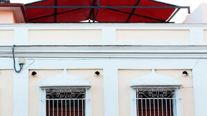 Facciata di un edificio con due finestre caratterizzate da inferriate decorative e un cartello con la scritta 'VACANCY'.