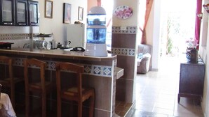 Una cucina con angolo bar, frigorifero e orologio a parete.