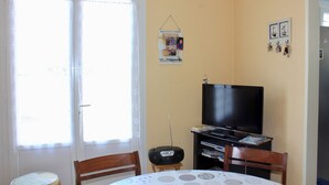 Una stanza con televisore, un tavolo con tovaglia a pois e una porta con tenda.