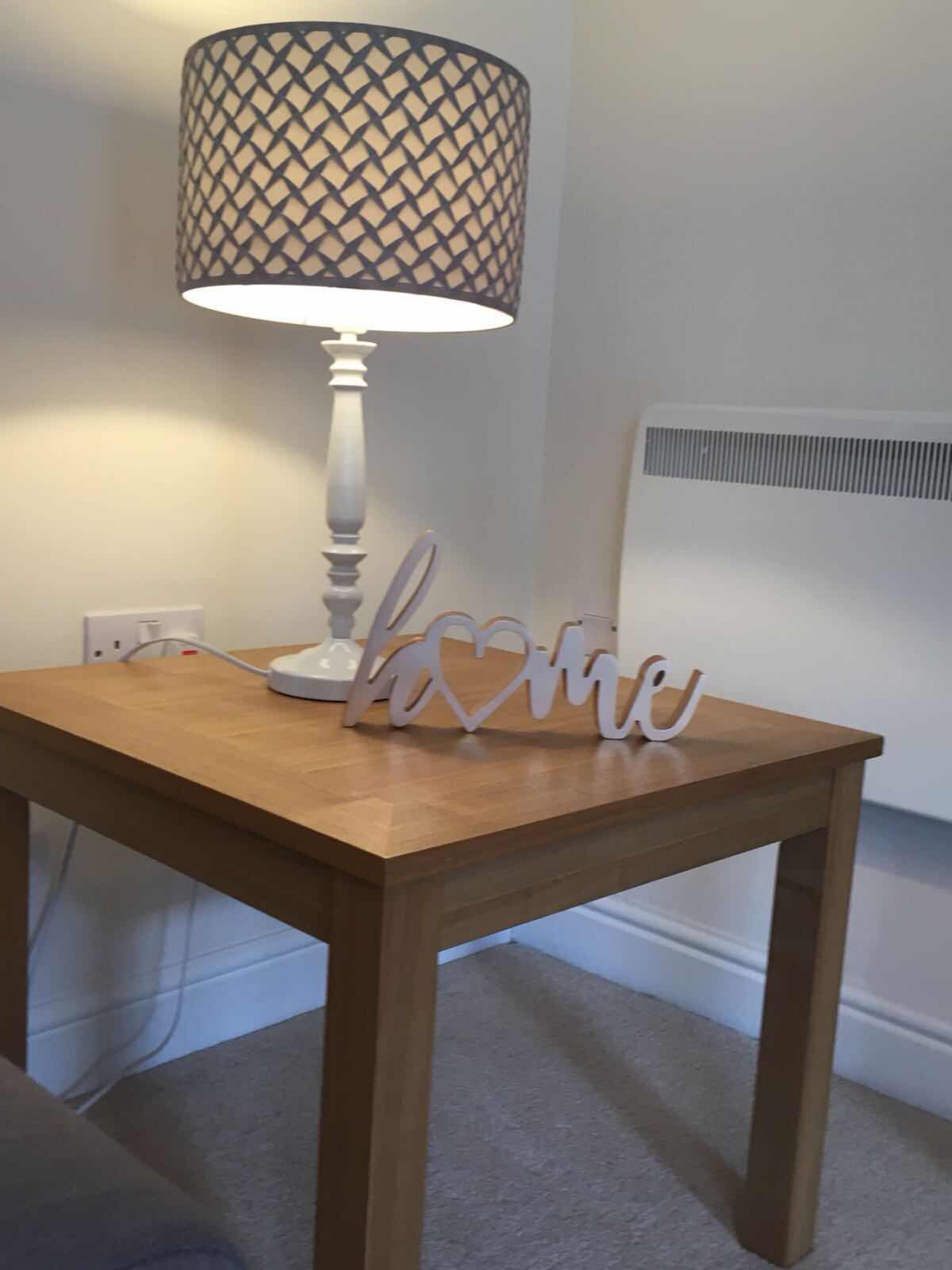 A wooden table with a white lamp and a 'love' decoration.
