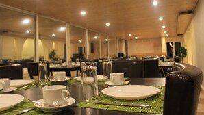 Un comedor con mesas dispuestas para el desayuno, incluyendo platos, tazas y cubiertos.