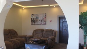 Una sala de estar con un sofá de cuero marrón, una mesa de centro y un cuadro de un paisaje urbano.