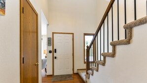 A hallway with a wooden door, a white door, and a carpeted staircase. - 5 Bedroom house with a Hot Tub and Home Theater! (Fort Collins)
