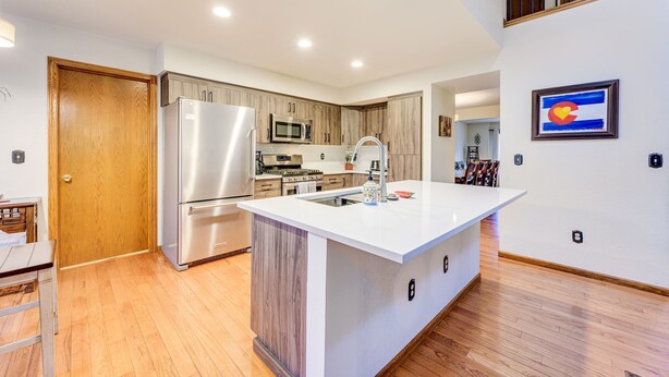 A modern kitchen with a central island, stainless steel appliances, and wooden cabinetry. - 5 Bedroom house with a Hot Tub and Home Theater! (Fort Collins)