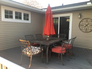 A covered patio with a table and chairs, a red umbrella, and a decorative wall piece.