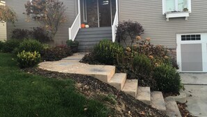 A two-story house with a front porch, stone steps, and a garage. - House on the 16th Tee! (Howard)