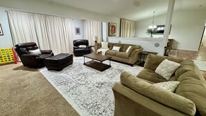 A living room with a brown sofa, two armchairs, a coffee table, and a patterned rug. - House on the 16th Tee! (Howard)