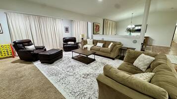Un salon avec un canapé marron, deux fauteuils, une table basse et un tapis à motifs.