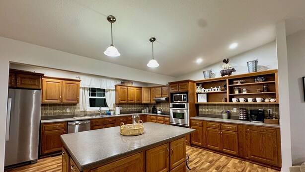 A modern kitchen with wooden cabinets, stainless steel appliances, and a central island. - House on the 16th Tee! (Howard)