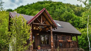 Eine rustikale Holzhütte mit einem steilen Satteldach, einer Holzterrasse und einem Schild, das sie als Berglodge kennzeichnet.