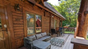 Eine Holzhütte mit einer Terrasse, einem Sofa und einem Tisch.